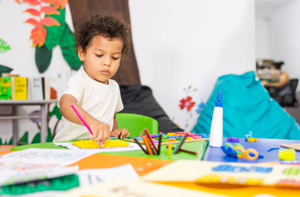 istock Cute child playing with modeling clay and colored pencils in kindergarten 2194428425