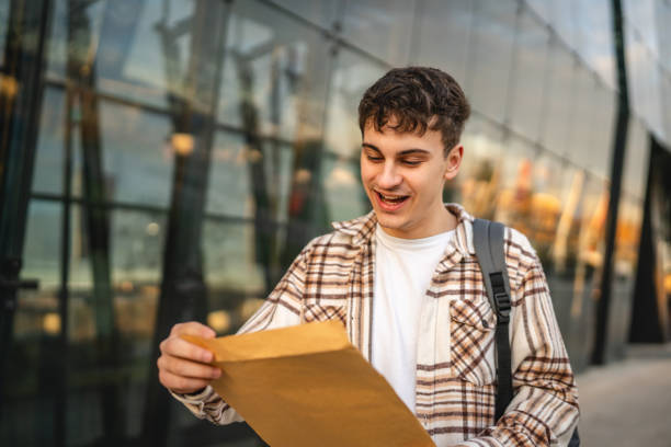 istock Young adult man student open and read files from envelope outdoor 2194430428