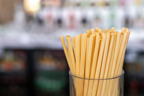 Bamboo straws stands in a glass container in cafe. Straws are made from natural wheat and cane stems. They are totally biodegradable, compostable, zero-waste and plastic-free. Eco-friendly concept.