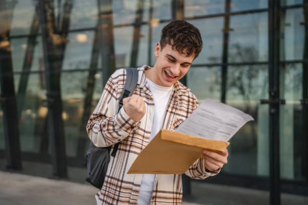 istock Young adult man student open and read files from envelope outdoor 2194430666