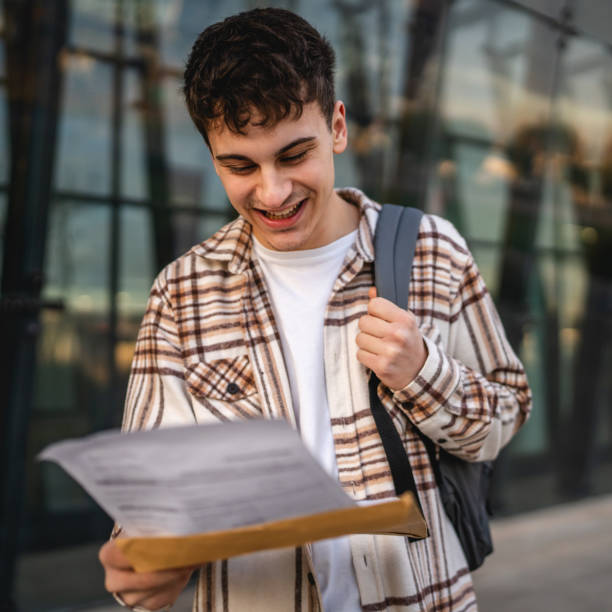 istock Young adult man student open and read files from envelope outdoor 2194430716