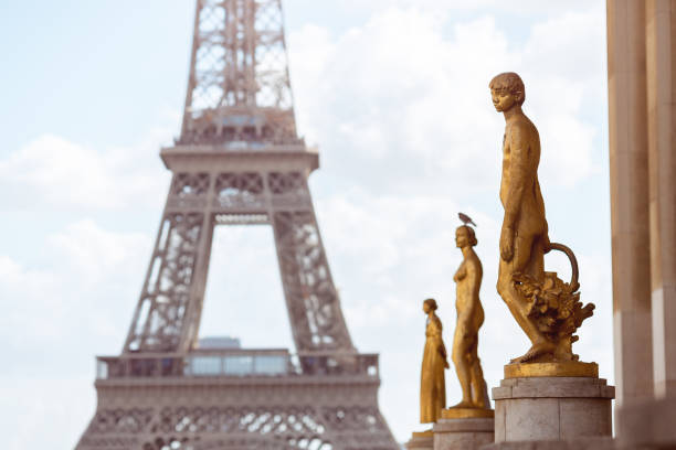 Elegant golden statues in the foreground with the Eiffel Tower in the background under a bright sky. A perfect image for cultural, travel, or Paris-themed promotional projects.