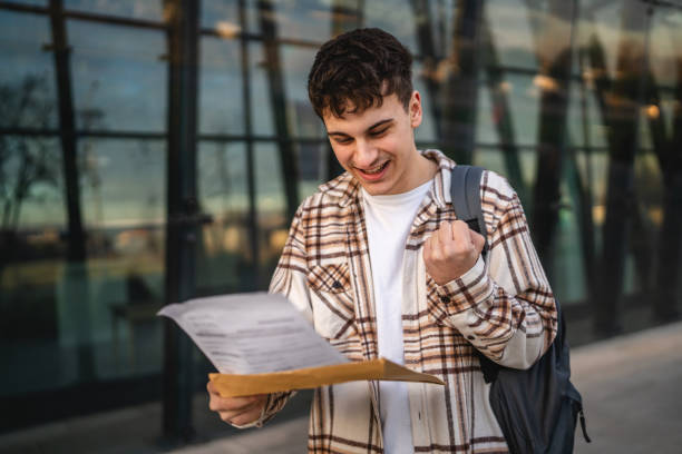istock Young adult man student open and read files from envelope outdoor 2194431184