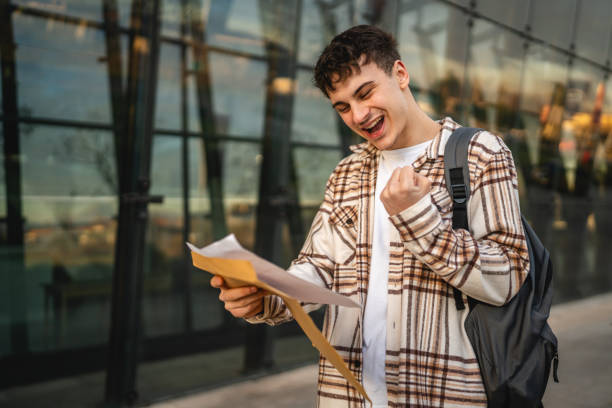 istock Young adult man student open and read files from envelope outdoor 2194431839