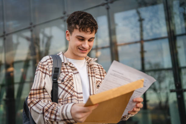 Young adult man student open and read files from envelope outdoor