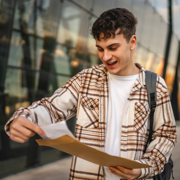 istock Young adult man student open and read files from envelope outdoor 2194432409