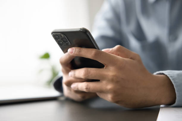 istock Unrecognizable man sitting at desk with smartphone in hands 2194432844