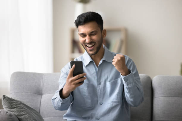 istock Indian man staring at mobile phone screen celebrate success 2194434688