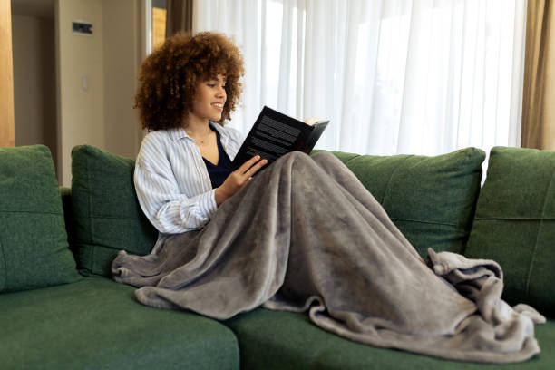 istock Beautiful Young woman sitting on a sofa and reading a book 2194439657
