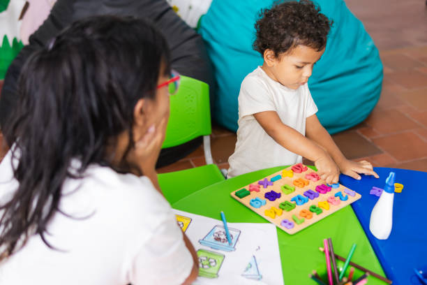 istock Little boy learning alphabet with colorful letters at kindergarten table with teacher 2194440152