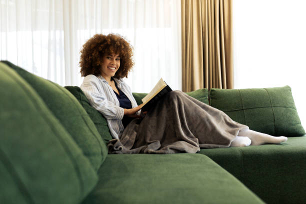 istock Beautiful Young woman sitting on a sofa and reading a book 2194443256