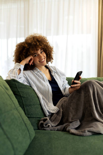 istock Beautiful Young woman sitting on a sofa and using her smart phone 2194443331