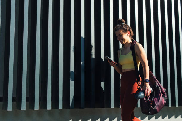 istock Fitness Enthusiast Using Smartphone Walking Near Modern Architectural Background 2194443689
