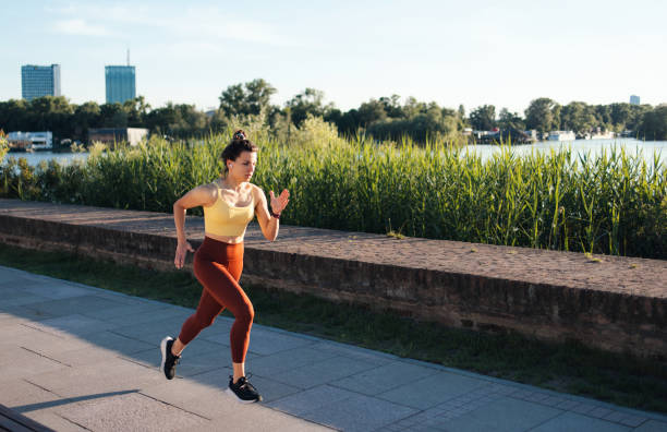 istock Female Jogger Exercising on Riverside Path with Urban Skyline in the Background 2194443740