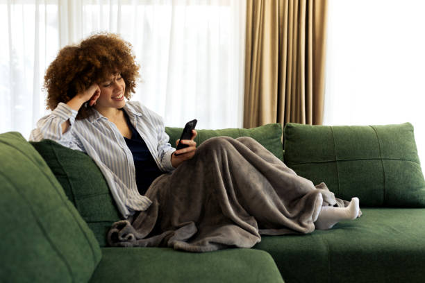 istock Beautiful Young woman sitting on a sofa and using her smart phone 2194445162