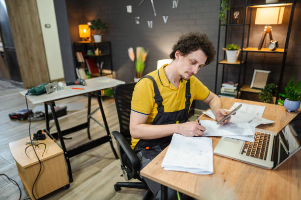 istock Handyman calculating expenses using smartphone and laptop in apartment 2194447646