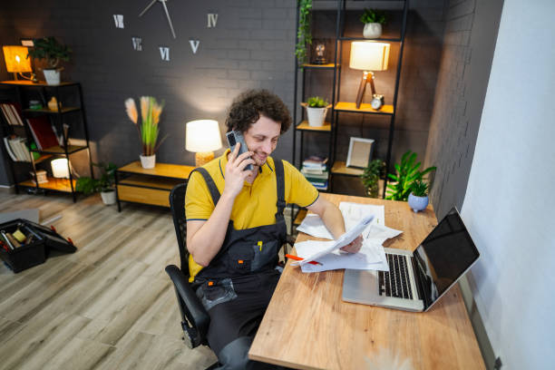 istock Handyman talking on the phone and reading documents at home office desk 2194447651
