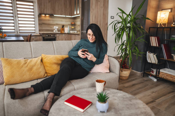 istock Woman relaxing on sofa using smartphone in modern apartment living room 2194447813
