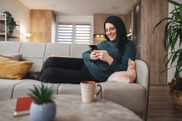 istock Woman relaxing on sofa using smartphone at home 2194447941