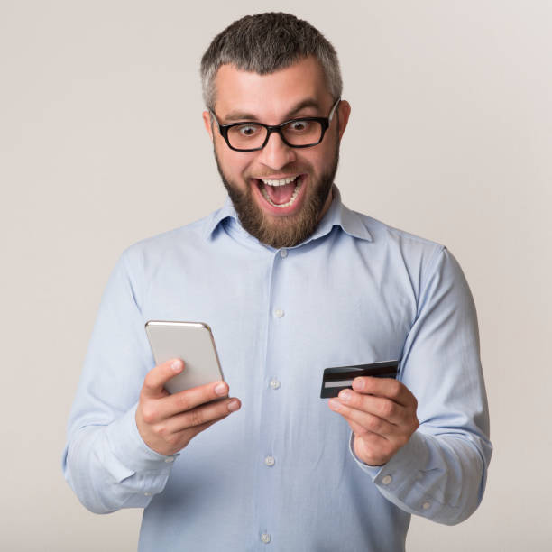 istock Man Excitedly Checking Mobile Payment With Smartphone and Credit Card 2194458544
