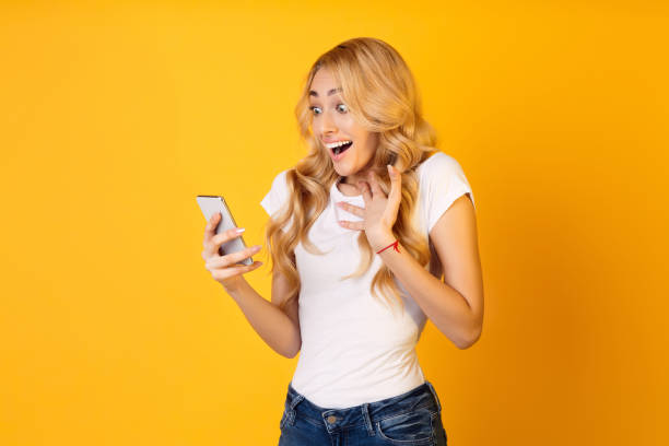 istock Excited Young Woman Reacting to a Surprise While Using Her Smartphone Against a Bright Background 2194461136