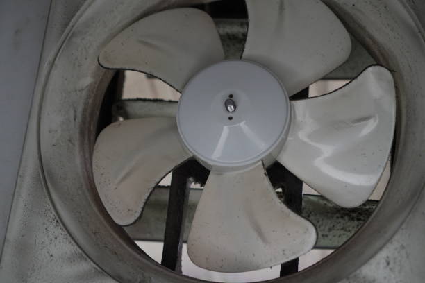 A weathered industrial fan, its blades caked in grime, yet still spinning. This close-up captures the raw beauty of a well-used tool, a testament to its resilience and functionality. The contrast between the dirty surface and the intricate details of the fan blades creates a visually striking image.