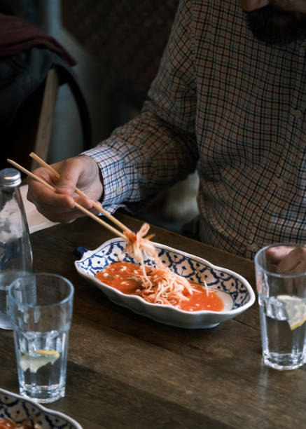istock Traditional Thai Papaya Salad Served in a Blue-Patterned Bowl with Fresh Ingredients and Spicy Dressing, Enjoyed with Chopsticks in a Cozy Restaurant Setting 2194478626