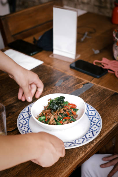 istock Traditional Thai Stir-Fried Hot Basil with Fresh Vegetables and Aromatic Spices Served in a White Bowl on a Blue-Patterned Plate in a Warm and Inviting Restaurant Setting 2194478660