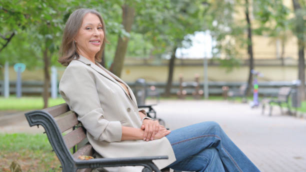 istock Smiling Old Woman Looking at Camera while Sitting on Bench 2194485254
