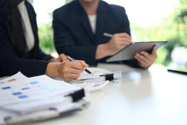 istock Close up of two businesspeople analyzing charts and documents at a desk 2194485310