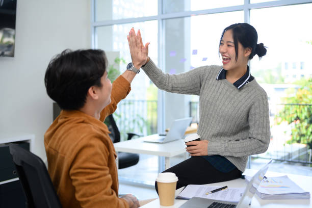 istock Two cheerful colleagues celebrating their successful cooperation with high five in modern office 2194485323