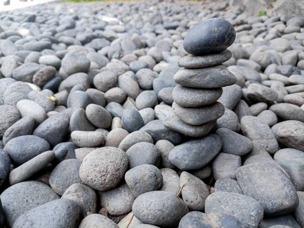 Stacked black spa pebbles on white background close up