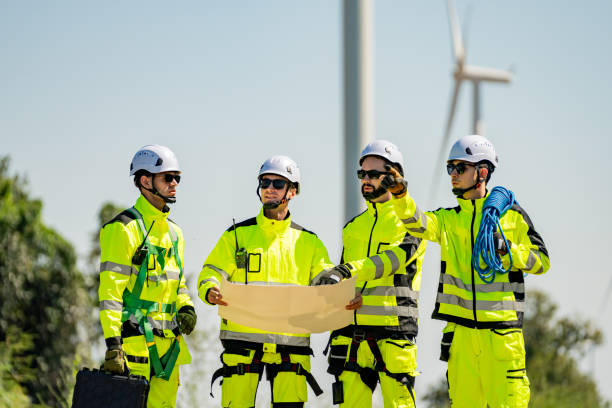 istock Skilled workers in bright safety gear analyze plans at a wind turbine site in bright sunlight during a workday 2194486824