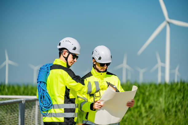 istock Engineers review plans for a wind farm project in an open field under a clear blue sky 2194486956