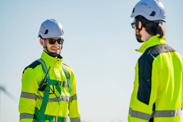 istock Construction workers communicate on a sunny day at a job site, showcasing safety gear and collaboration 2194487500