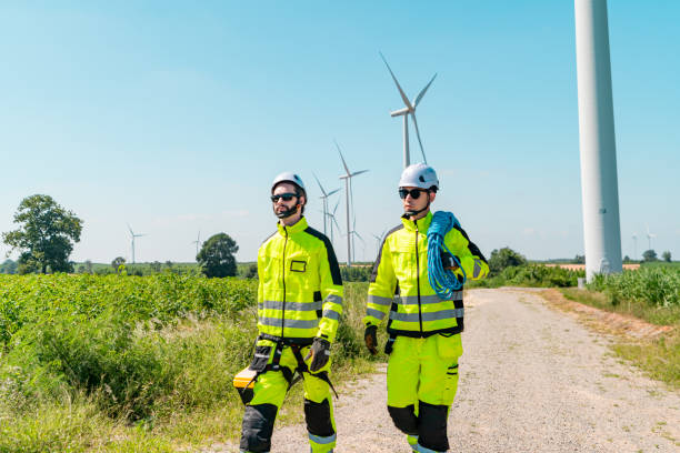istock Two technicians walking along a pathway in a wind farm wearing safety gear during bright daylight 2194487511