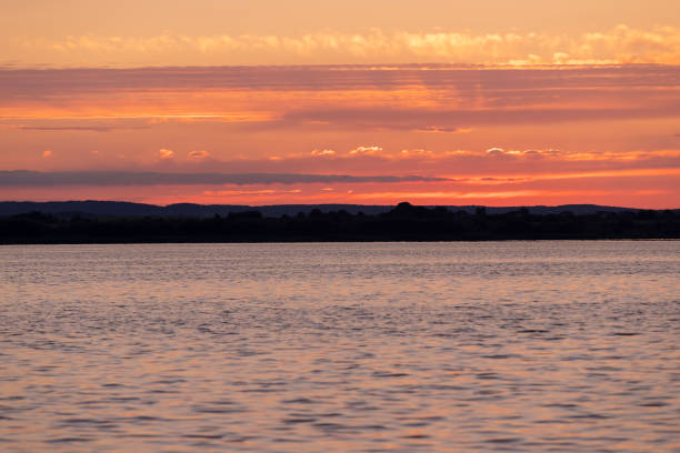 sunset with sun and orange sky on the lake, reflection of the orange sky in the waves on the lake during sunset