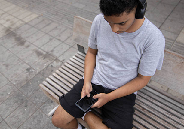 Latino guy wearing wireless headphones and using his phone