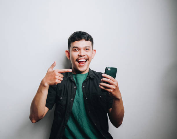 istock Joyful Young Man Pointing at His Smartphone Against a Minimalist Background 2194496316