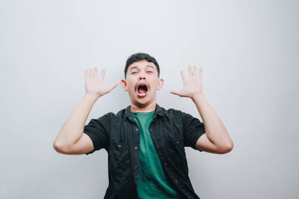 A young man displays surprise and excitement in a minimalist setting.