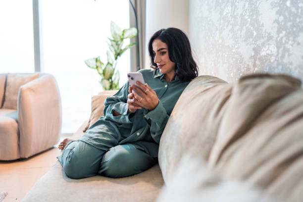 istock Smiling Young Woman in Comfortable Home Using Smartphone 2194497547