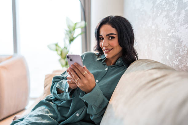 istock Smiling Arabic Woman Relaxing with Smartphone in Modern Home 2194497551