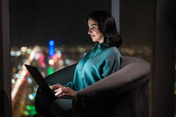 istock Focused Arabic Woman Using Laptop Overlooking Riyadh's Night Skyline 2194497698