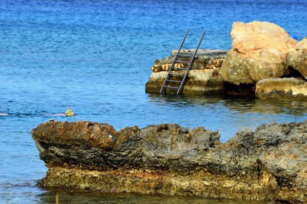 istock ladder on the rock for descending into the sea 2194497751