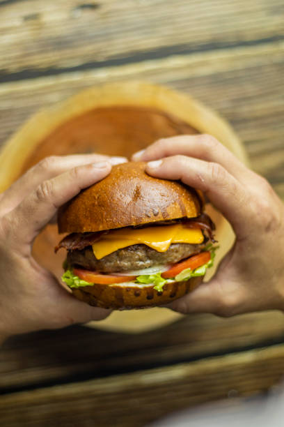 istock Fresh Cheeseburger with Lettuce, Tomato, and Cheese on a Wooden Plate 2194498691
