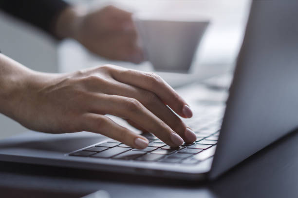 istock Female hands in sharp focus typing on a modern laptop keyboard, office environment in soft blur behind 2194499357