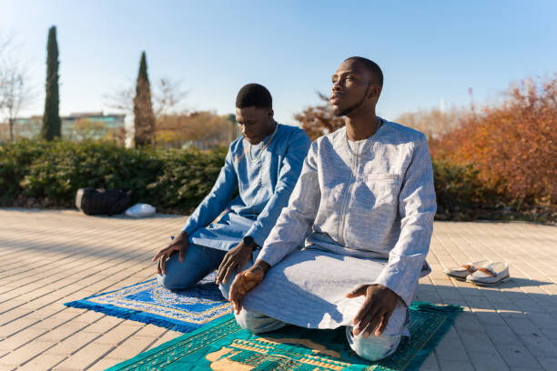 Two senegalese muslim men praying outdoors during ramadan