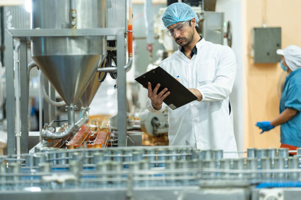istock Inspector checking automated machinery in food production facility Focus on quality control safety and workflow efficiency. Worker overseeing food packaging machinery in a modern manufacturing plant. 2194508581
