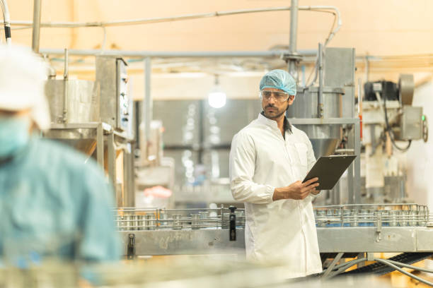 istock Inspector checking automated machinery in food production facility Focus on quality control safety and workflow efficiency. Worker overseeing food packaging machinery in a modern manufacturing plant. 2194508706