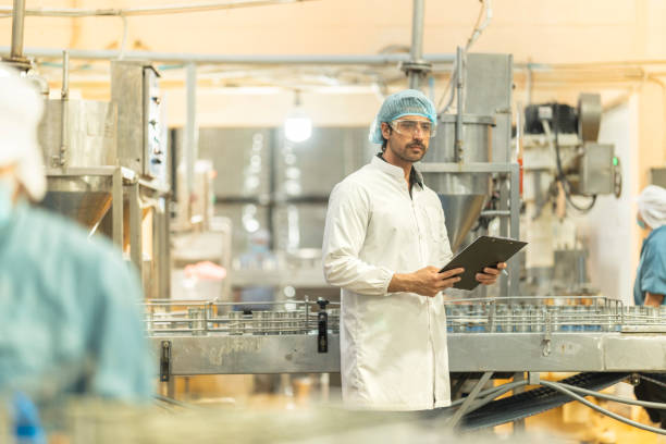 istock Inspector checking automated machinery in food production facility Focus on quality control safety and workflow efficiency. Worker overseeing food packaging machinery in a modern manufacturing plant. 2194509448